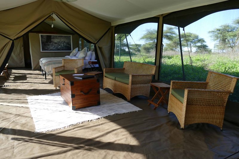Family tent living room with cane armchairs and a wooden chest on a woven rug