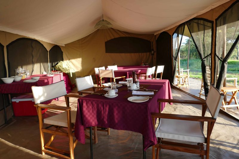 Dining tent with tables laid with red cloths and director's chairs