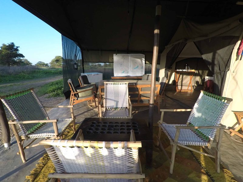 Lounge veranda with woven chairs around a low table, a map board behind