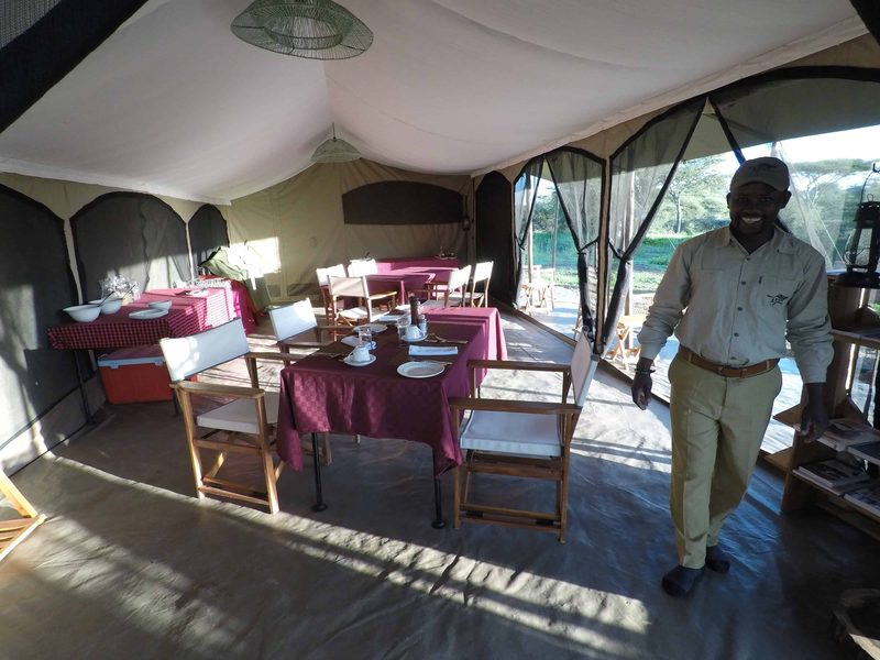A staff member in the dining tent, tables laid with red cloths