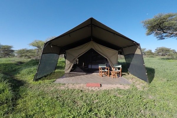 A guest tent from the front, door open, two chairs on a mat outside