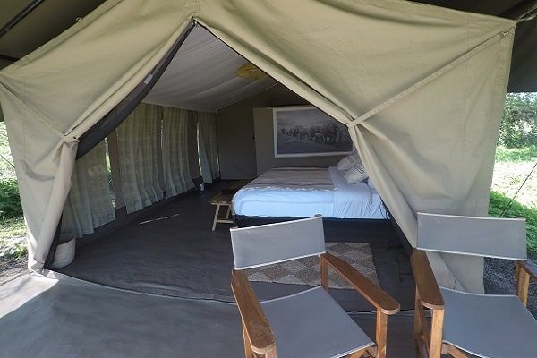 Looking into a guest tent past two director's chairs to the bed