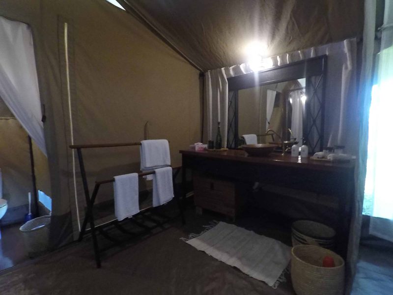 Dressing area in a guest tent with a wooden vanity, mirror and towels