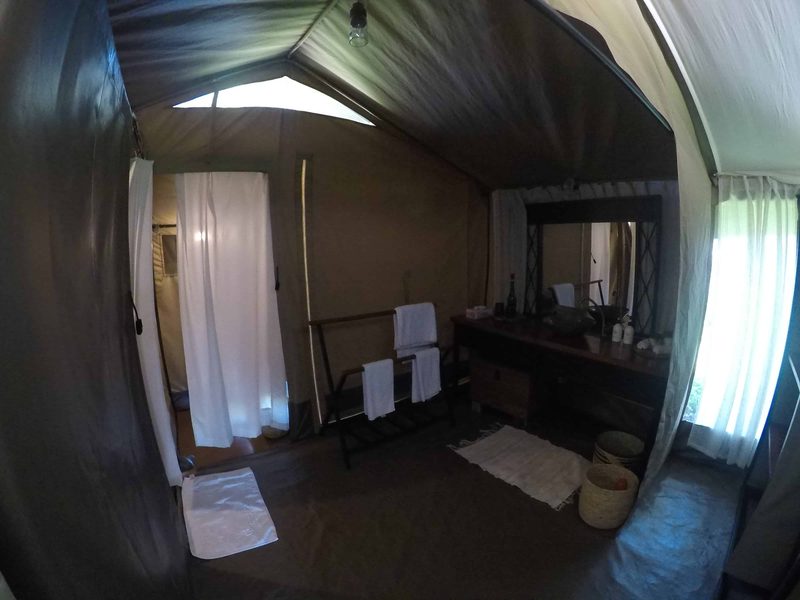 Guest tent dressing area with a vanity, mirror, towels and the shower curtain