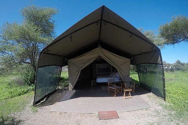 A guest tent seen from the front, door open, with two chairs on the veranda