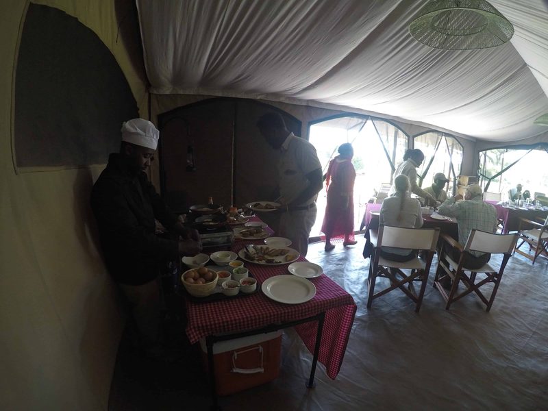 Staff serving a buffet in the dining tent while guests eat