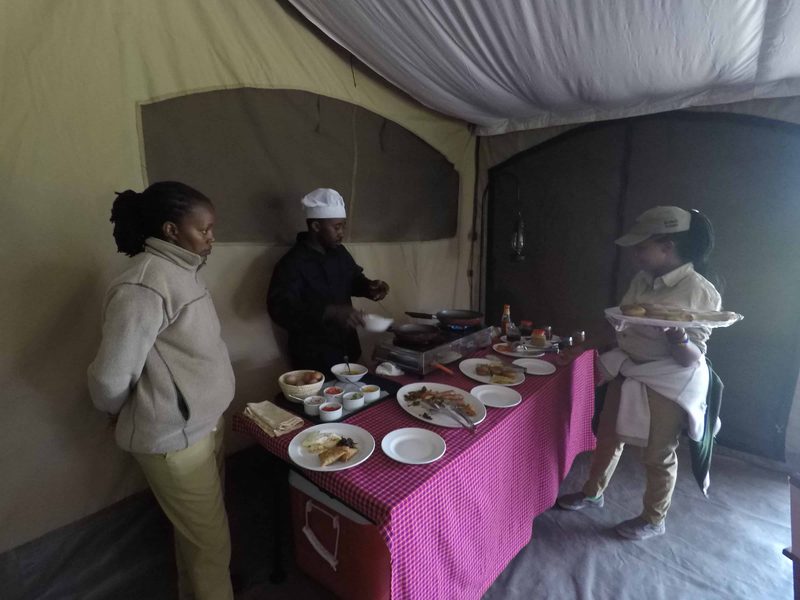 Camp staff behind a buffet table set with dishes in the dining tent