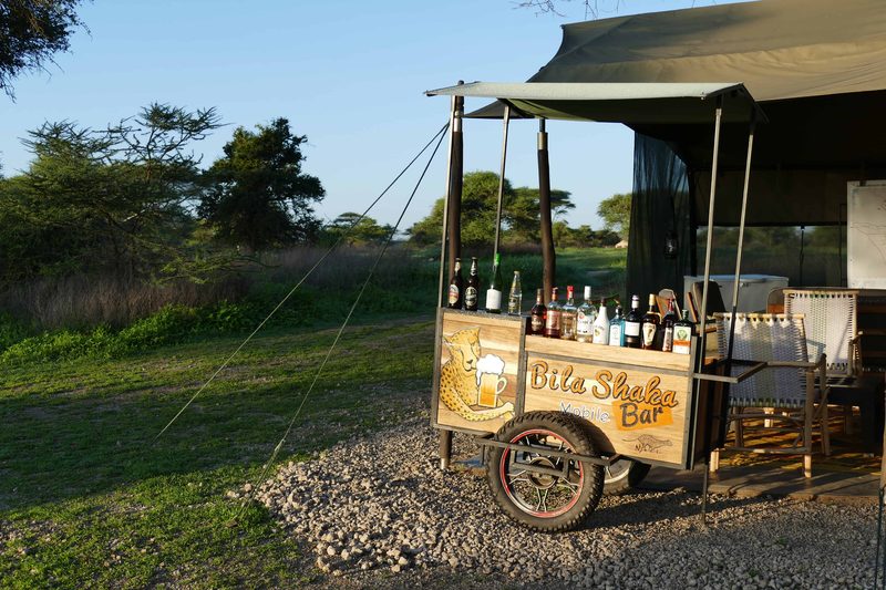 The camp's Bila Shaka bar cart, stocked with bottles, outside the mess tent