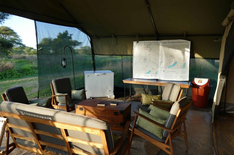 Lounge tent with cushioned sofas, a map board and a cooler